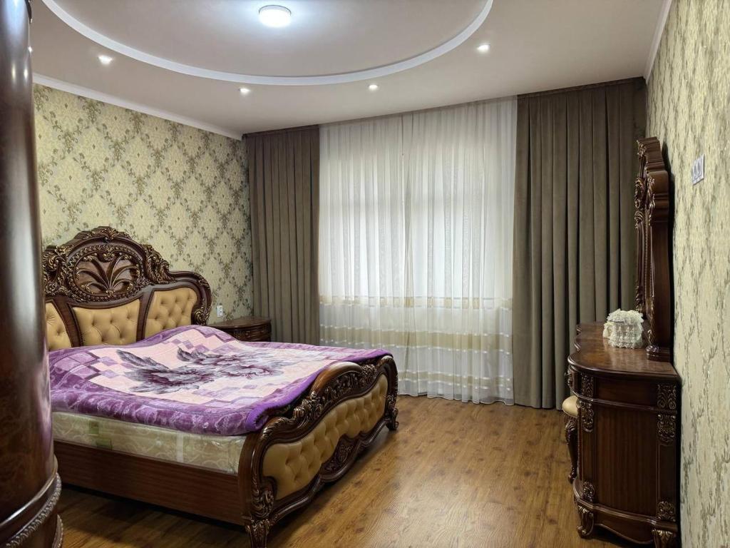 um quarto com uma cama com lençóis roxos e uma janela em Юнусабад шахристан люкс em Yunusobod