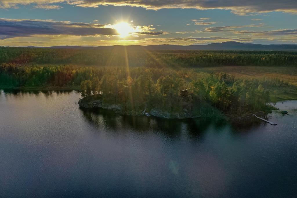 an island in the middle of a lake at sunset at VESI - The White Blue Wilderness Lodge in Inari