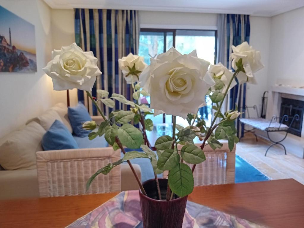 un jarrón lleno de rosas blancas sobre una mesa en Apartamento Albufeira 6 B, en Albufeira