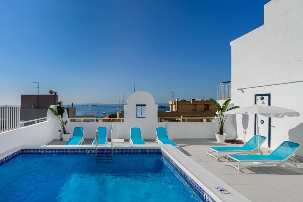 una piscina con sillas y sombrillas azules en Hotel Vibra Vila, en Ibiza