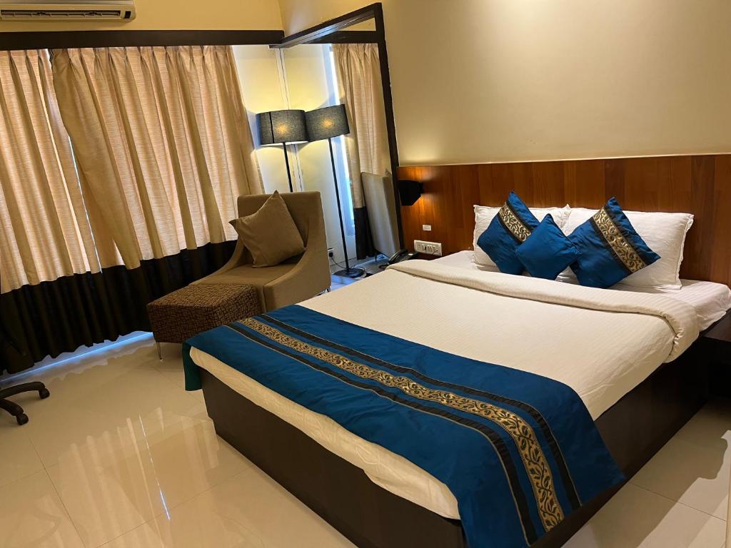 a hotel room with a large bed and a chair at Hotel Landmark Ratnagiri in Ratnagiri