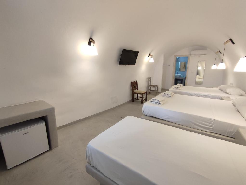a white room with two beds and a tv at Central Santorini Serenity Rooms in Fira