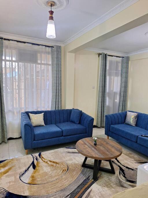 Sala de estar con sofás azules y mesa de centro en Angie's staycation 1 br apt Milimani, en Kisumu