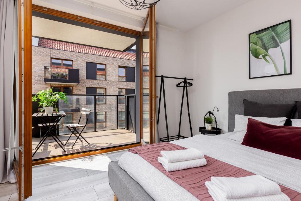 a bedroom with a bed and a view of a balcony at Palm Aparts Gdańsk in Gdańsk