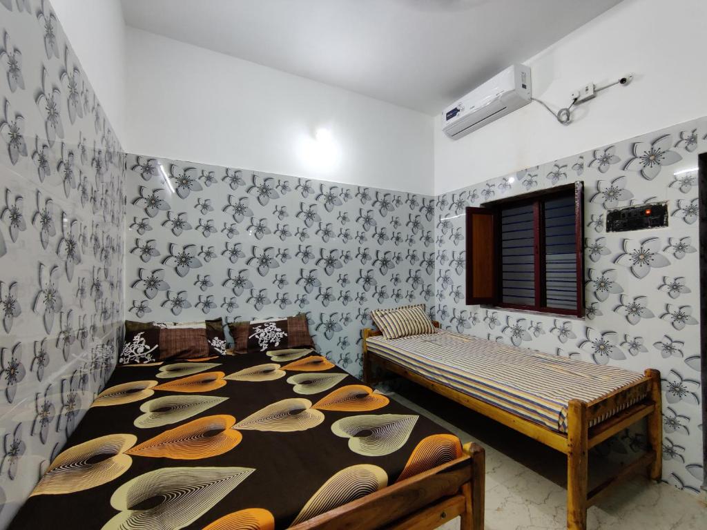 a bedroom with two beds and a wall with wallpaper at SIVA LODGE in Rāmeswaram