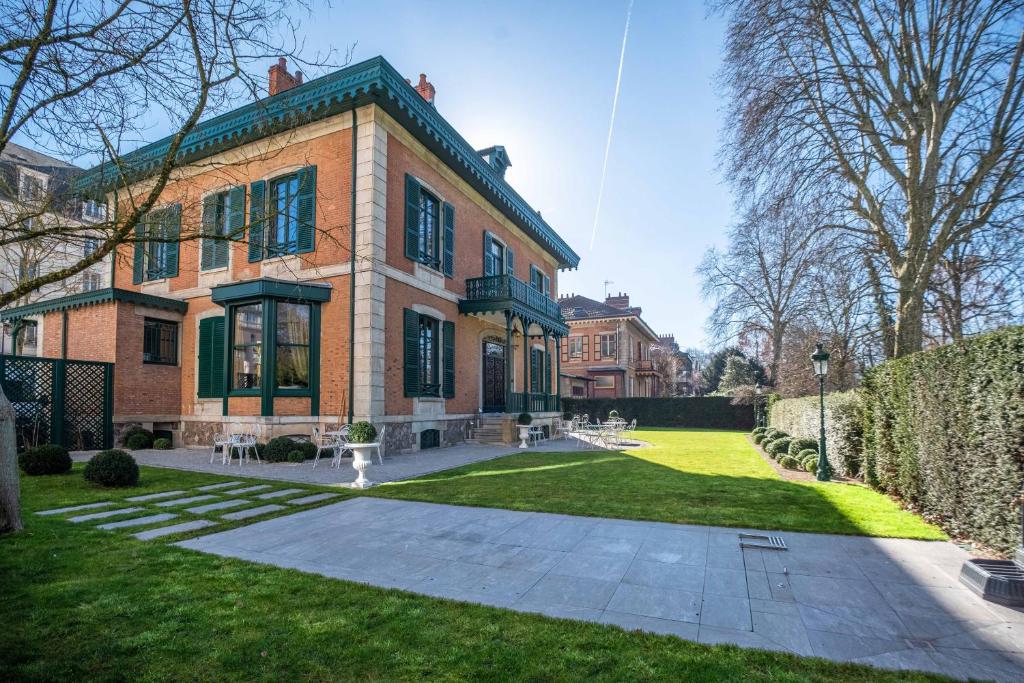 uma grande casa de tijolos com um quintal verde em 4 chambres au Chalet Clermont-Tonnerre + piscine em Vichy