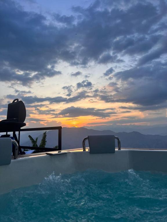 een zwembad met 2 stoelen en de zonsondergang bij Glamping Oro Verde in Santa Fe de Antioquia