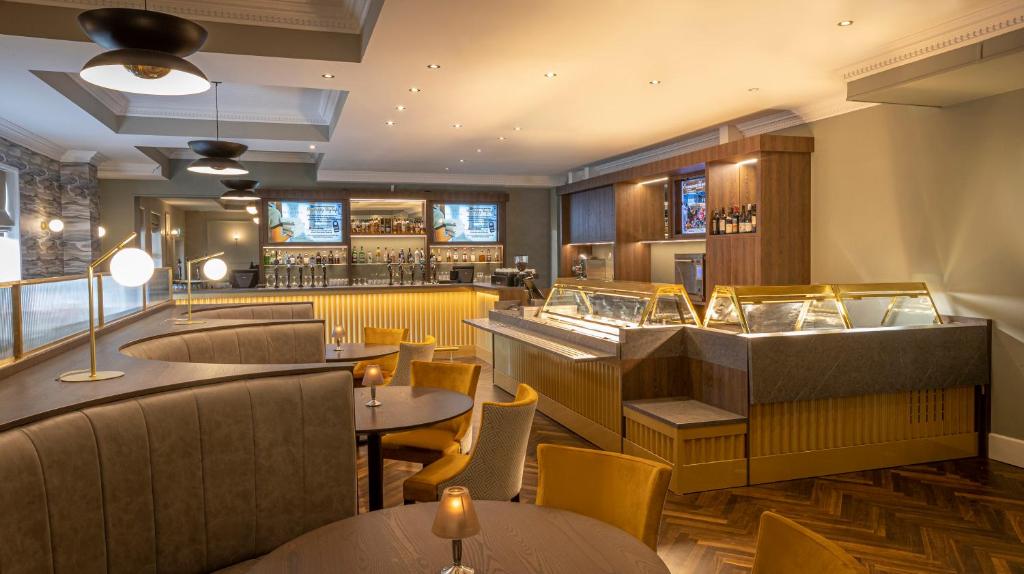 Modern lounge with colorful chairs, plush sofas, large windows, and chandeliers.