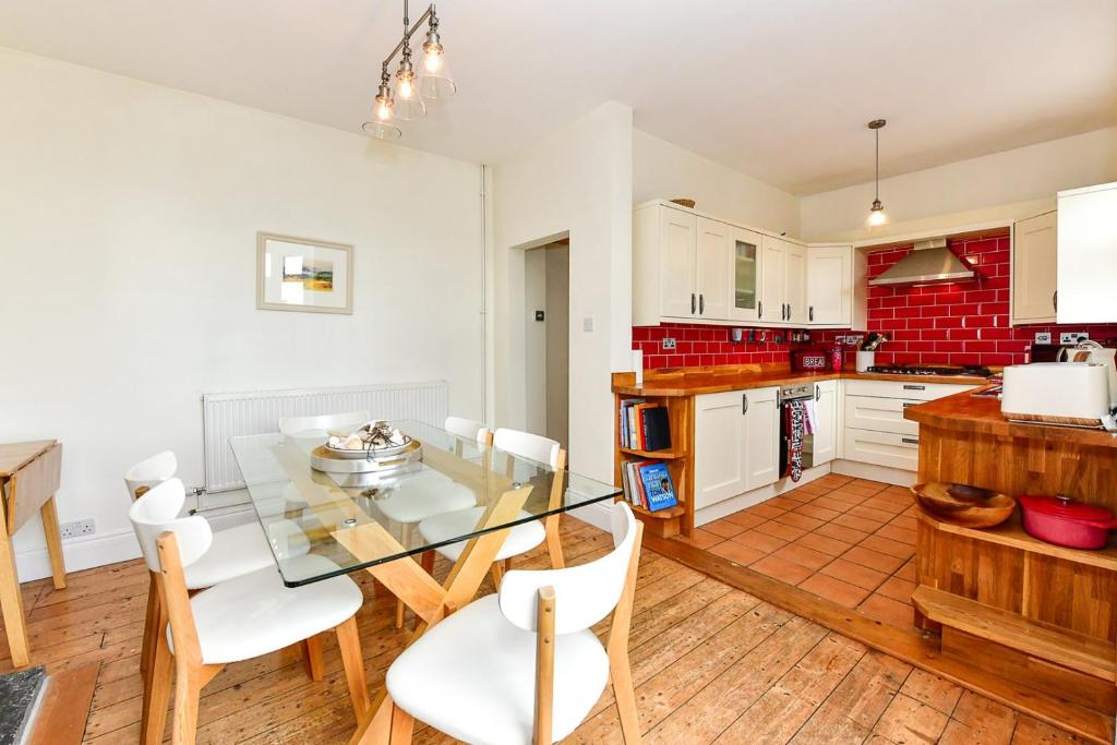 une cuisine avec une table en verre et des chaises blanches dans l'établissement Beautiful family home in Mumbles, with garden, à Mumbles