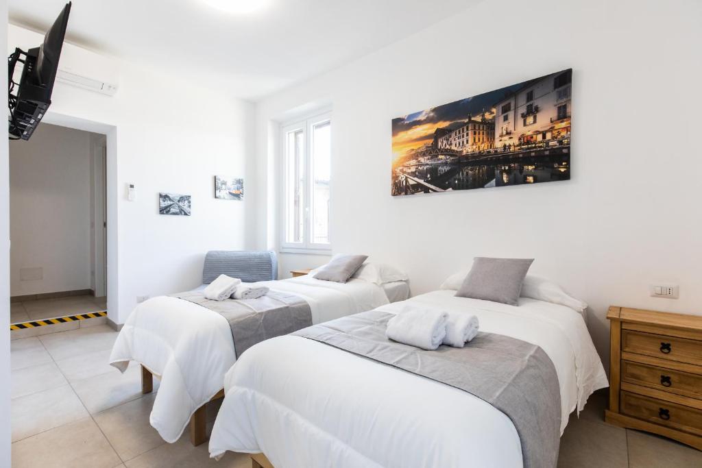 três camas num quarto com um quadro na parede em CityHouse Fm StationRho Fair Near center em Rho