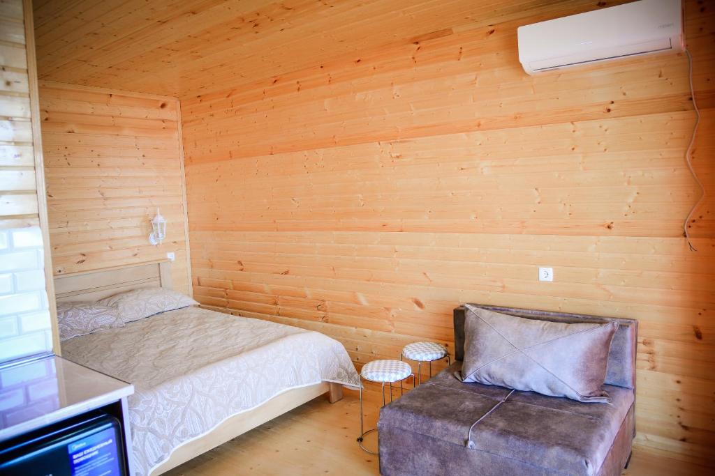 ein kleines Schlafzimmer mit einem Bett und einem Stuhl in der Unterkunft Arkhilo's cottage in Dedoplis Tskaro