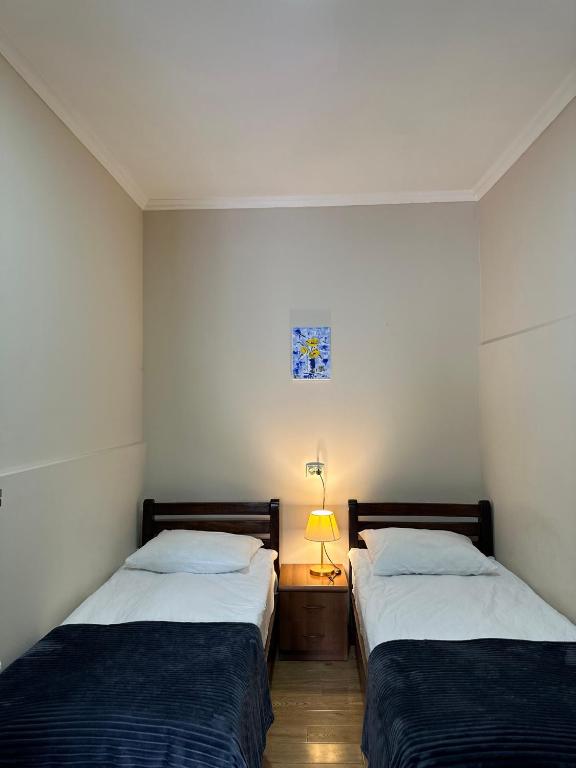 a bedroom with two beds and a lamp on a table at Meshia Apartment in Kazbegi
