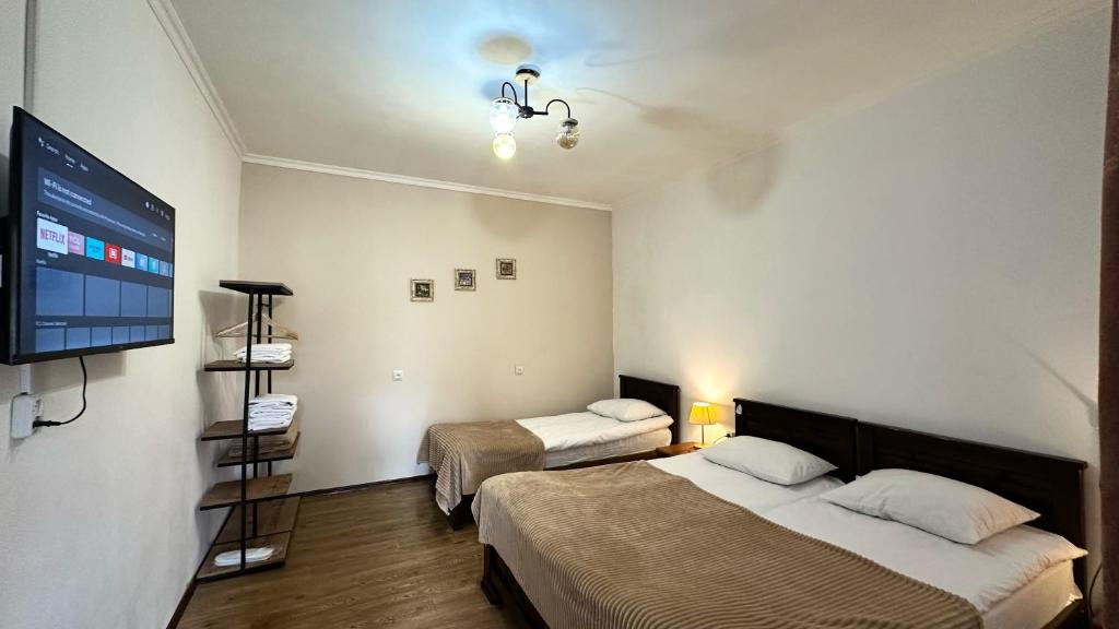 a room with two beds and a flat screen tv at Meshia Apartment in Stepantsminda