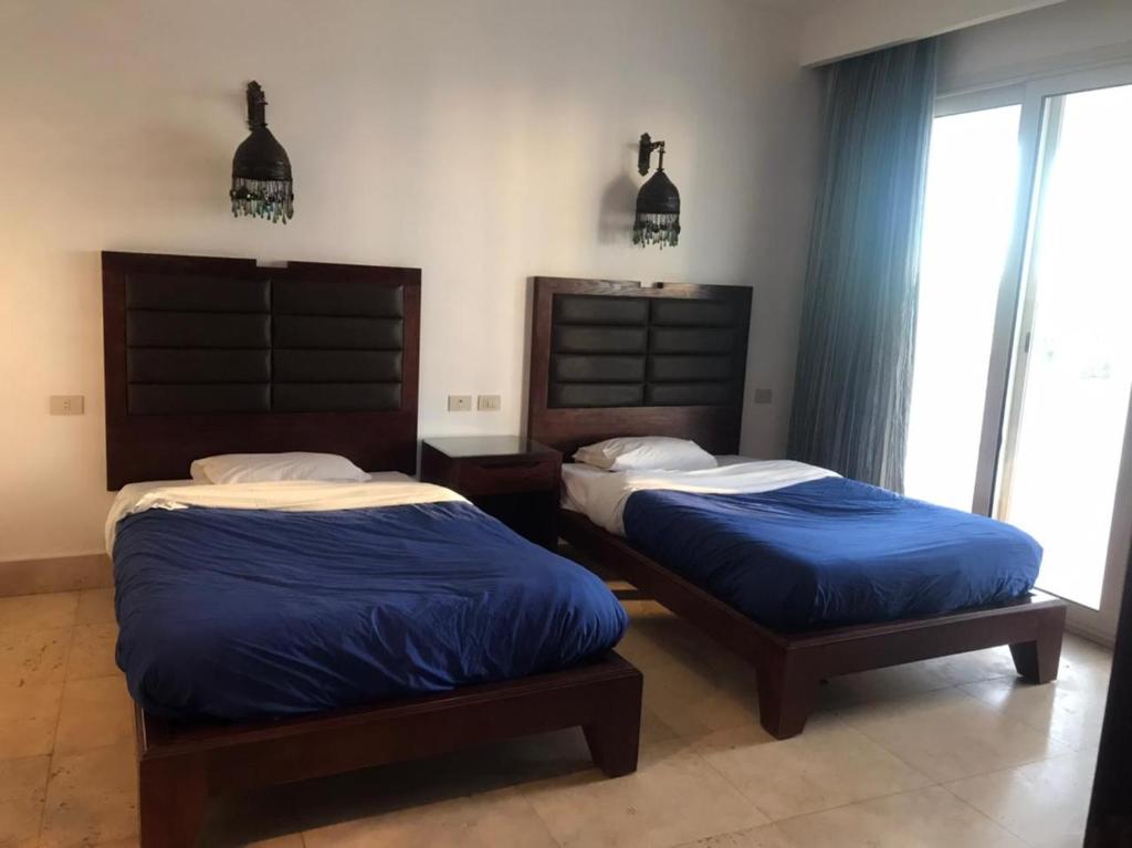 samara villas luxury في شرم الشيخ: سريرين في غرفة نوم مع ملاءات زرقاء