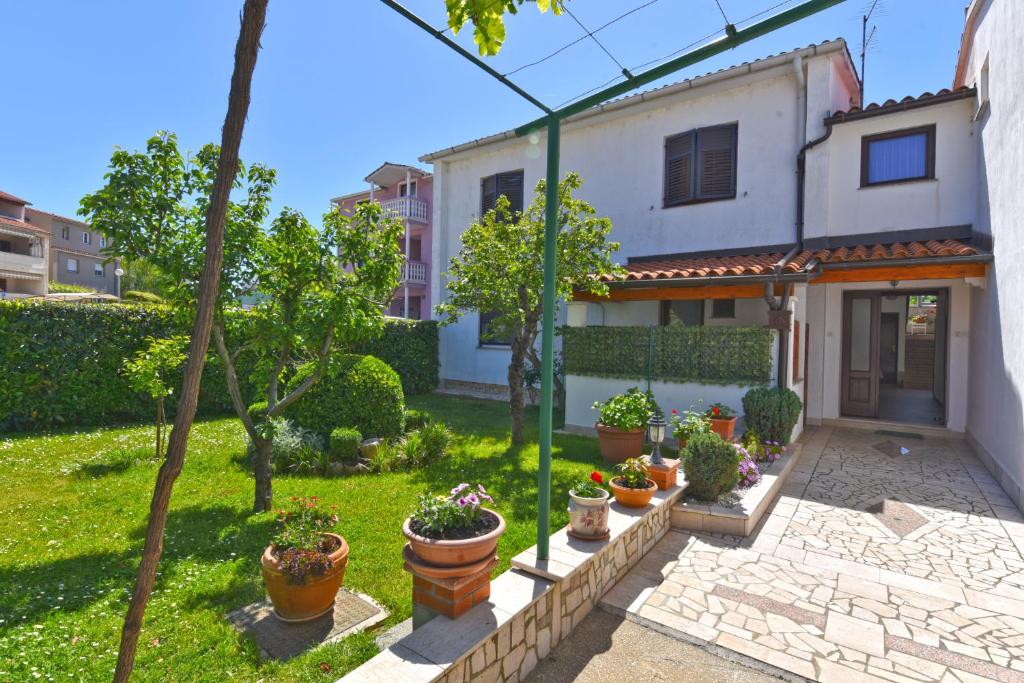 a house with potted plants in a yard at Apartments Nevina 1230 in Pula