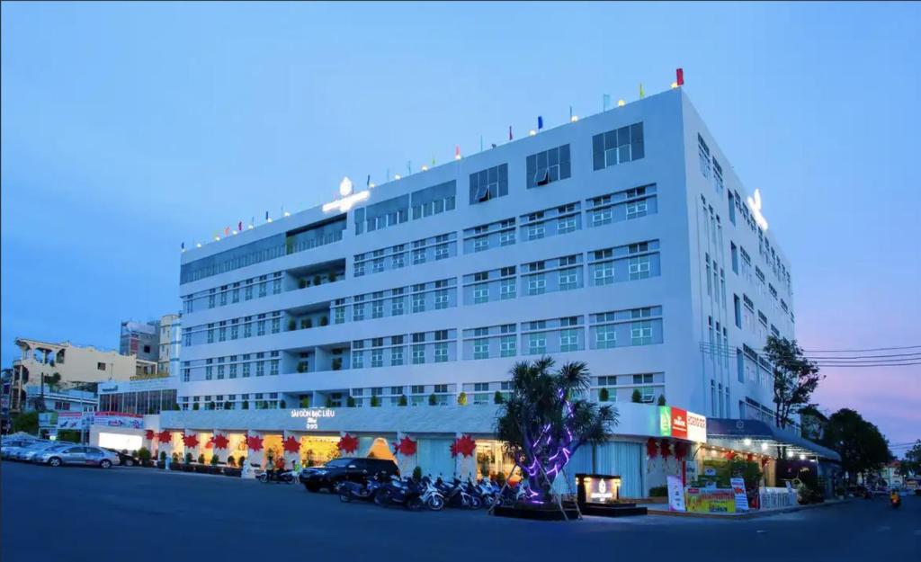um grande edifício branco com motos estacionadas em frente em SÀI GÒN - BẠC LIÊU Hotel em Bạc Liêu