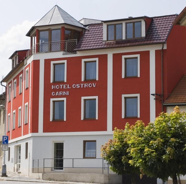 een rood-wit gebouw met de woorden hotel douane tram bij Hotel Ostrov Garni in Sadská