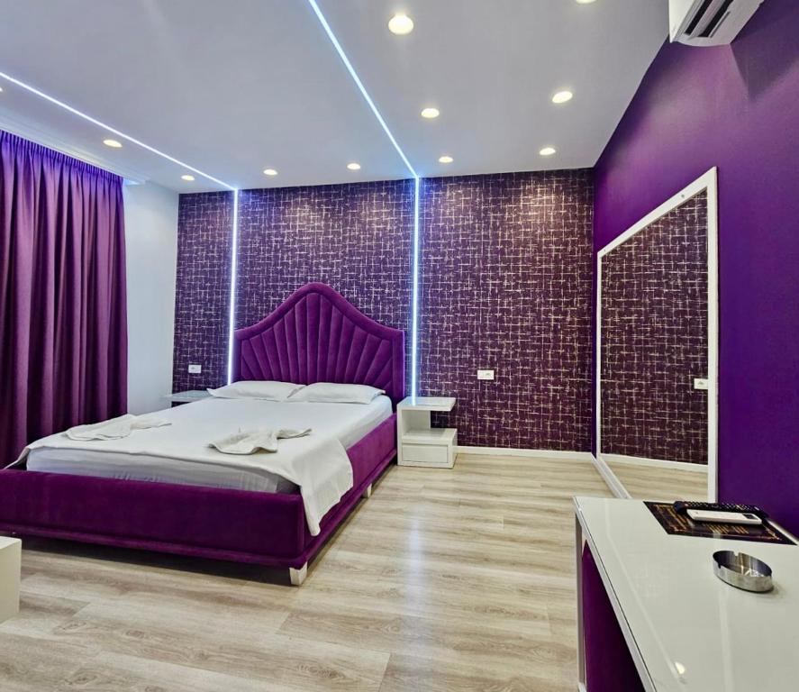 een paarse slaapkamer met een groot bed en paarse muren bij Hotel MoonLight in Fier