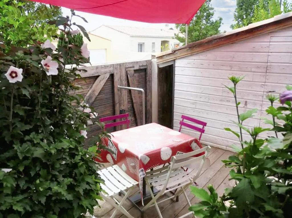 um pátio com uma mesa e cadeiras num deque em Maison de 2 chambres avec jardin clos et wifi a La Rochelle em La Rochelle