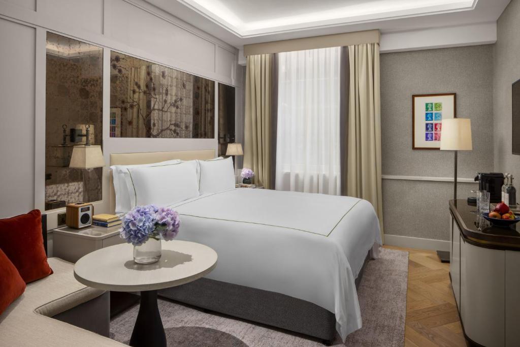 a bedroom with a large white bed and a table at The Biltmore Mayfair in London