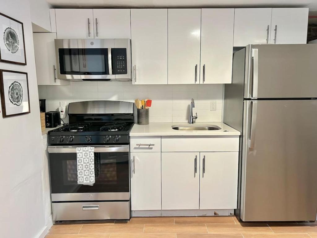 La cuisine est équipée de placards blancs et d'un réfrigérateur en acier inoxydable. dans l'établissement 0230-Central Cozy 2B 1B, à Hoboken