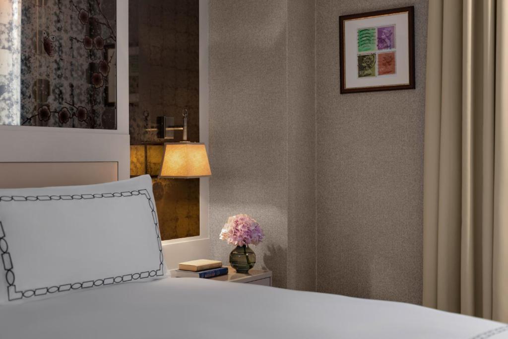 a bedroom with a bed and a lamp and flowers at The Biltmore Mayfair in London