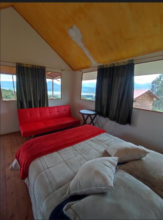 una camera da letto con un letto grande e un divano rosso di El Mirador de Juan a Guasca