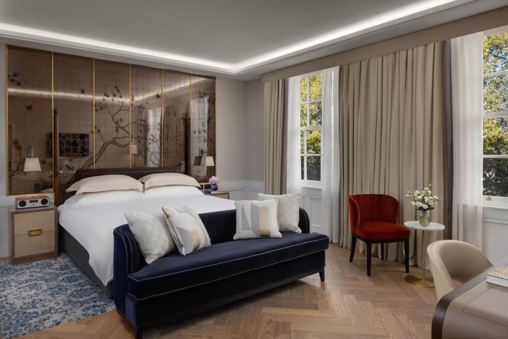 1 dormitorio con 1 cama grande y 1 sofá azul en The Biltmore Mayfair, en Londres