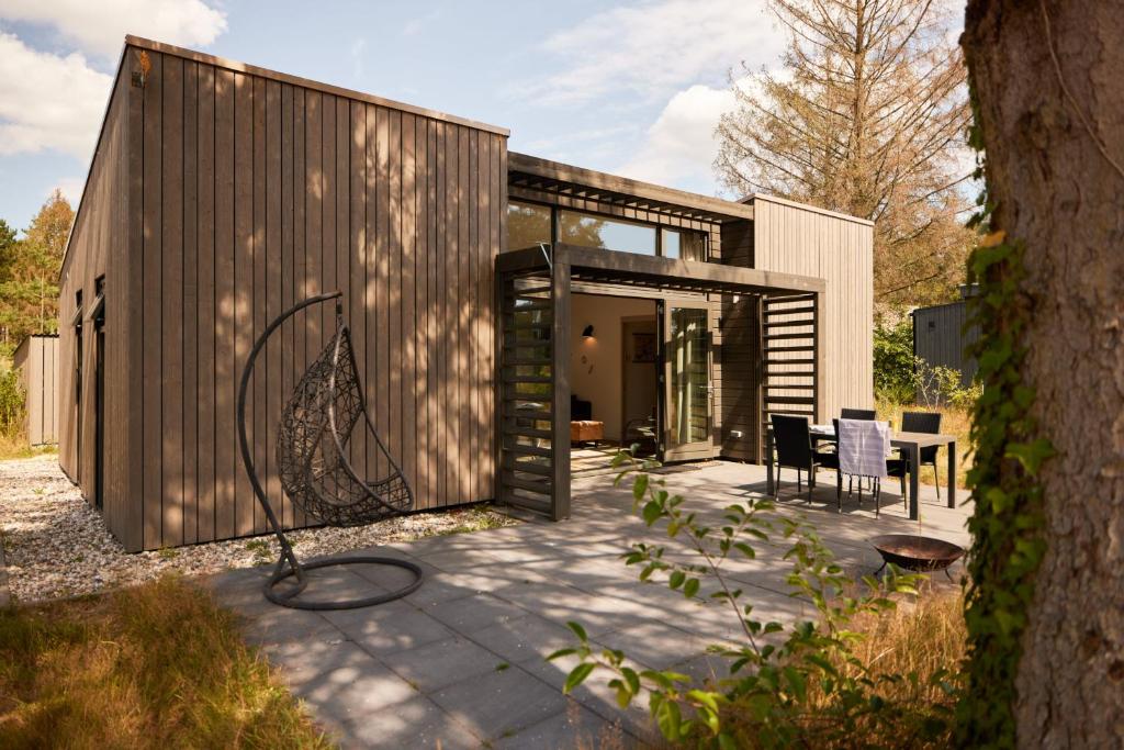 a small wooden house with a table and chairs at Dutchen Zeegser Duinen Suitelodges in Zeegse