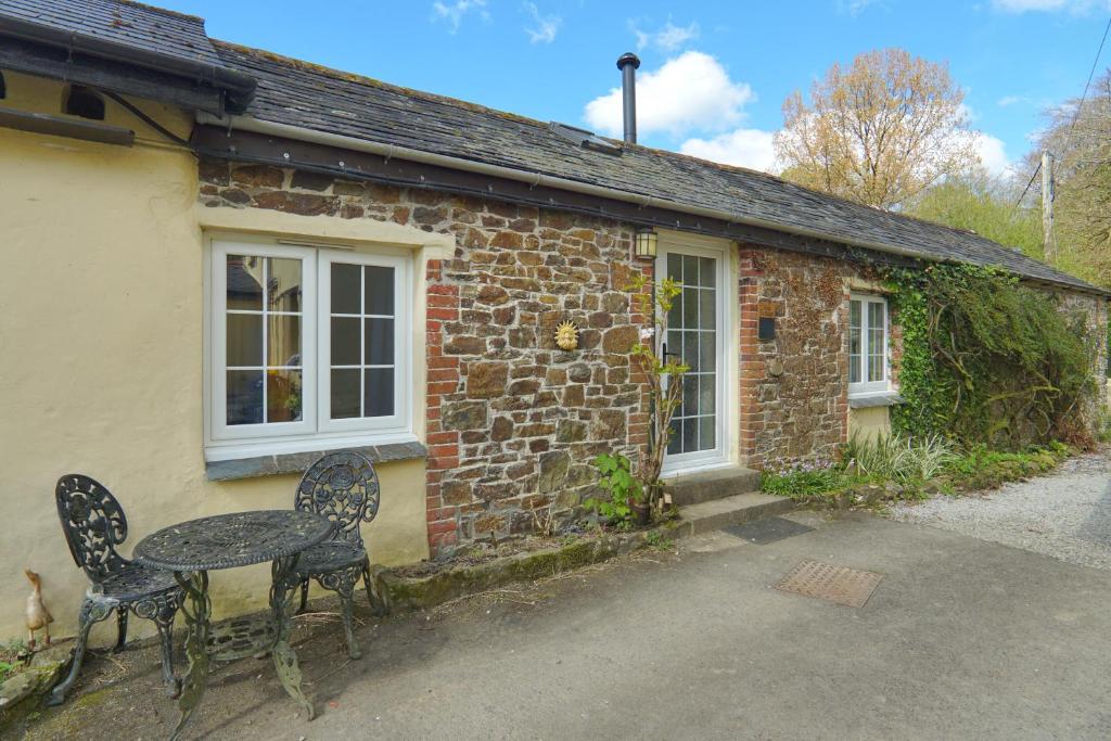 a table and chairs in front of a brick house at 1 Bed Cottage - Hot Tub Pool Wifi Pets in Holsworthy