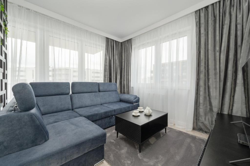 a living room with a blue couch and a table at Luksusowy Apartament z 3 Sypialniami, Klimatyzacją, Parkingiem i Biurkiem we Wrocławiu by Renters Prestige in Wrocław