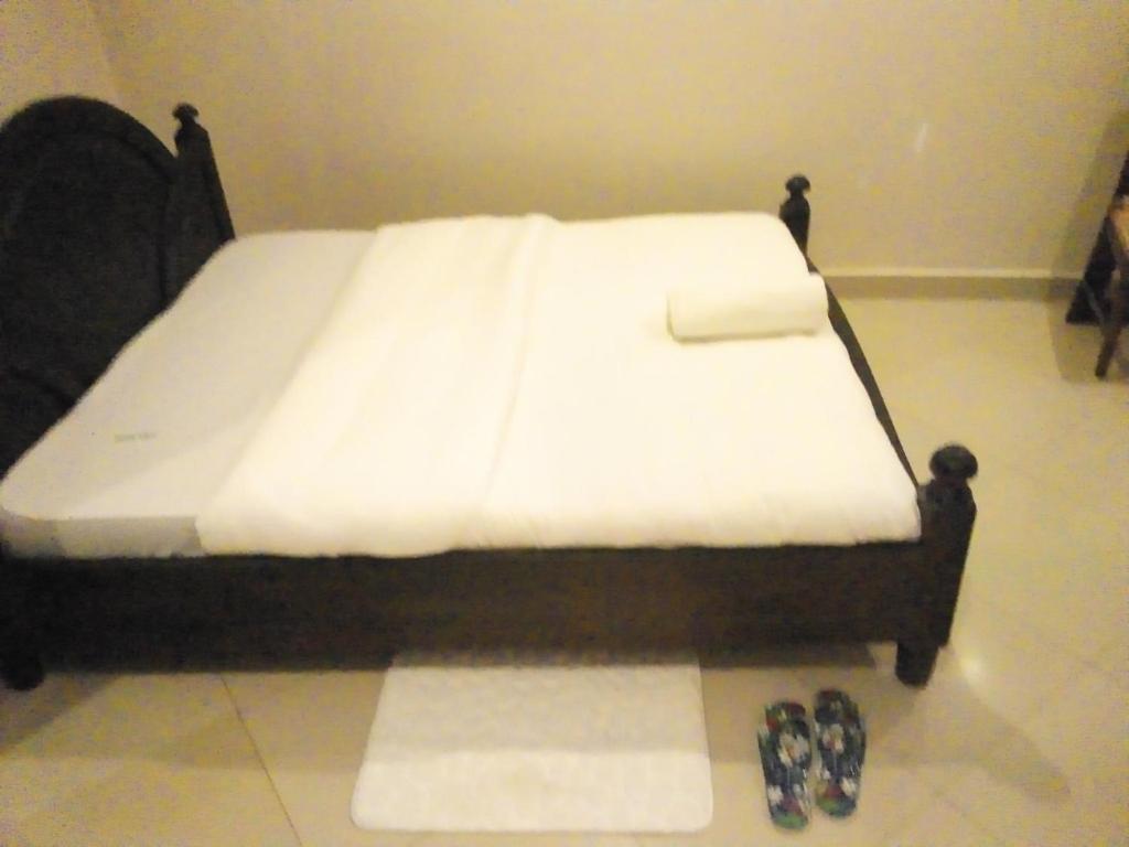 uma cama com lençóis brancos e dois pares de sapatos em Suzie hotel old Kampala em Kampala