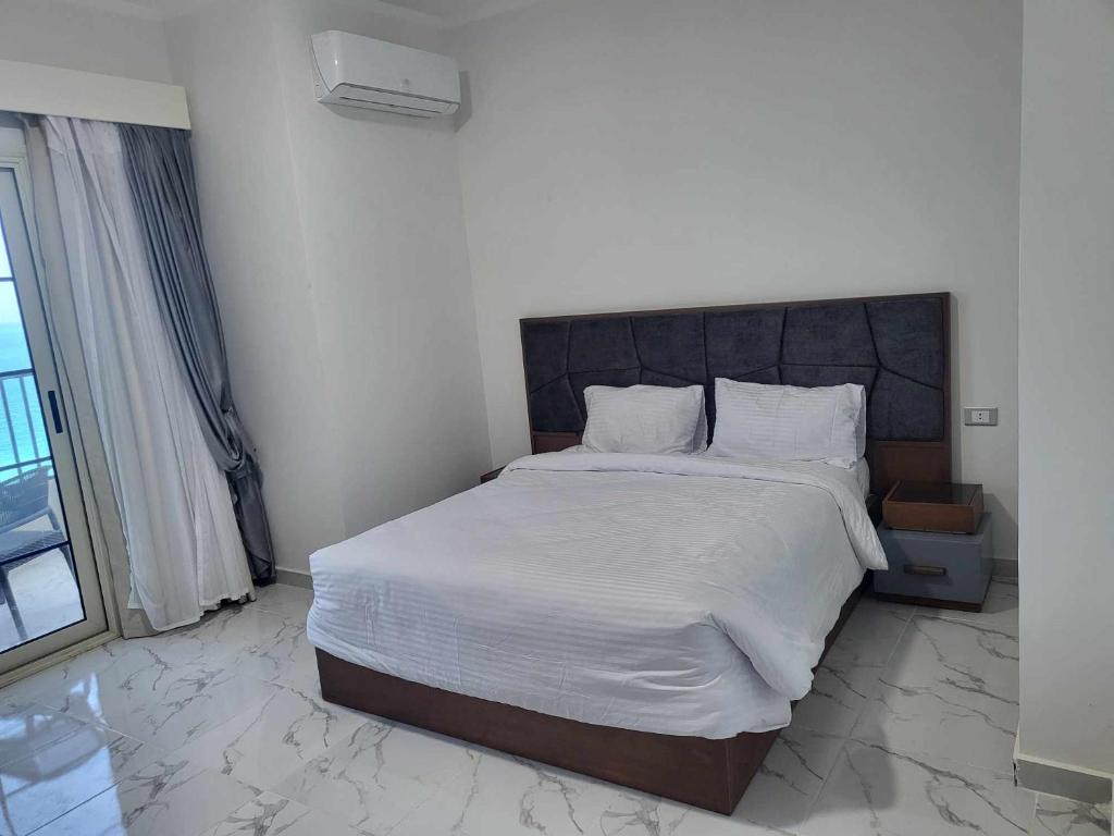 een slaapkamer met een groot bed met witte lakens bij SAMA Beach Resort in Hurghada