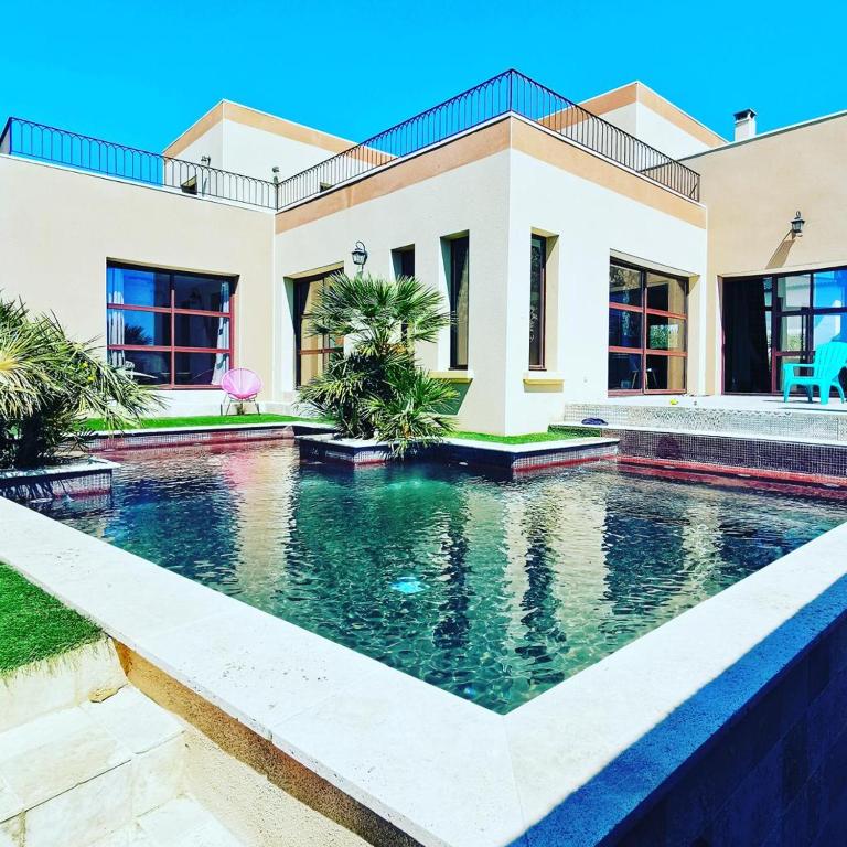 une piscine devant une maison dans l'établissement Magnifique villa atypique de 230 m2 avec patio intérieur, à Sauvian