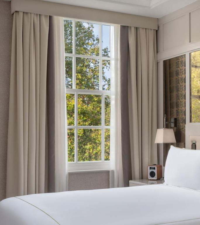 a bedroom with a bed and a large window at The Biltmore Mayfair in London