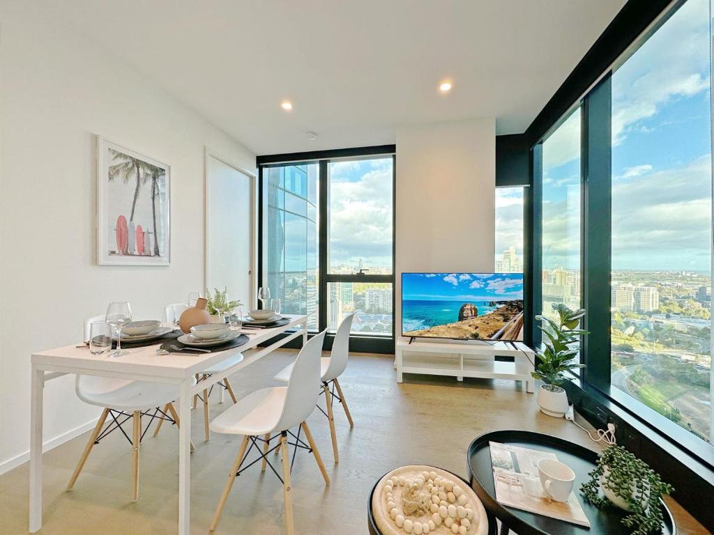 a dining room with a white table and chairs and large windows at Melbourne Luxury Apartment Steps away from Crown in Melbourne