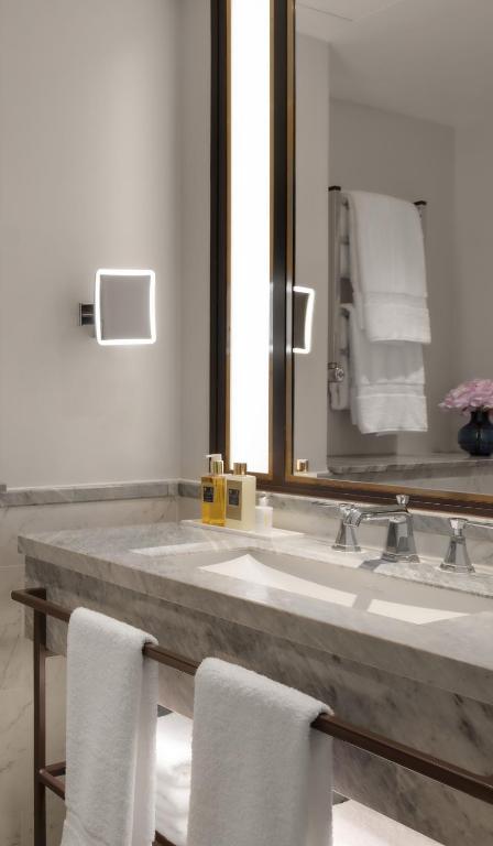 a bathroom with a sink and a mirror and towels at The Biltmore Mayfair in London