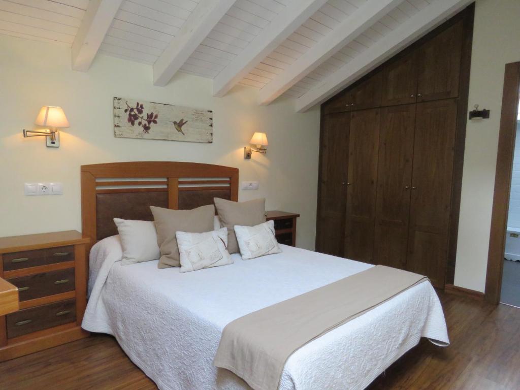 a bedroom with a white bed with a wooden headboard at Pensión Arbidel in Ribadesella