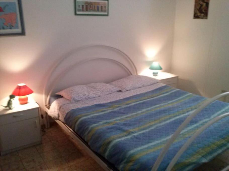 1 dormitorio con 1 cama con 2 mesitas de noche y 2 lámparas en Apartment for holiday rent in Marina di Cecina, en Cecina