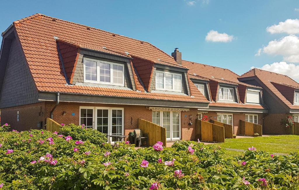 uma fila de casas com flores cor-de-rosa no quintal em 2 Bedroom Beautiful Apartment In Dithmarschen em Friedrichskoog-Spitz