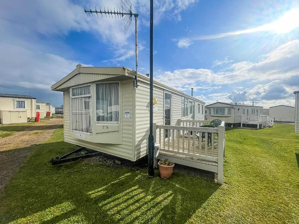 a tiny house on the grass in a yard at 6 Berth Caravan With Decking Nearby Heacham Beach In Norfolk Ref 21047a in Heacham