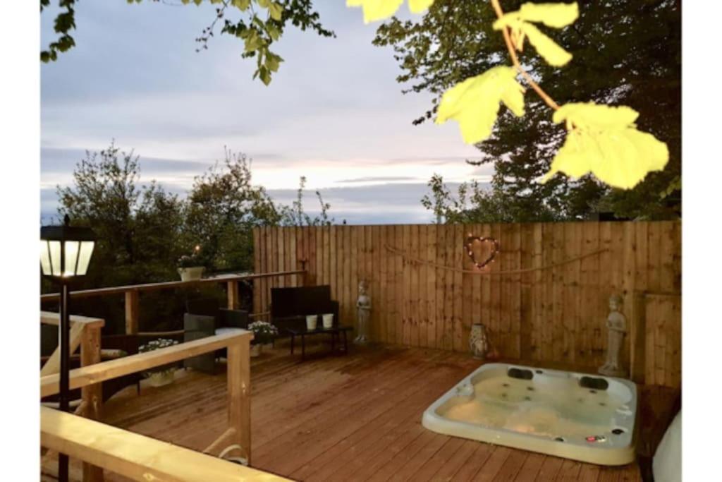 bañera de hidromasaje en una terraza de madera con una valla en Detached Bungalow Private Hot Tub With Log Burner, en Torquay