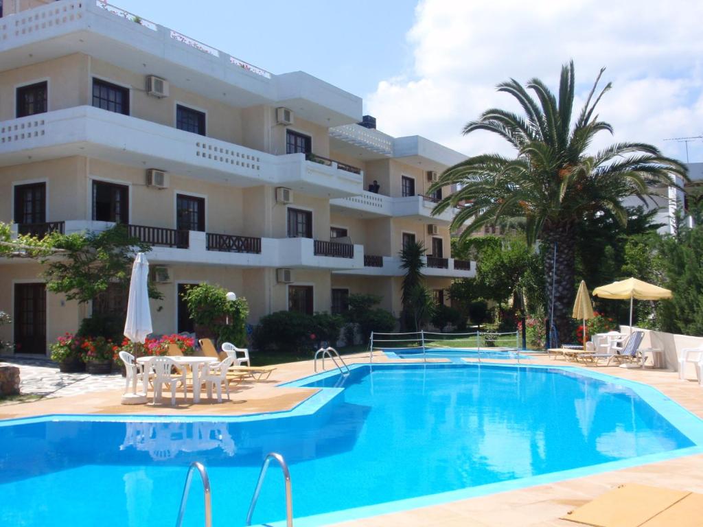 a hotel with a swimming pool in front of a building at Alexandros Studios in Kalamaki