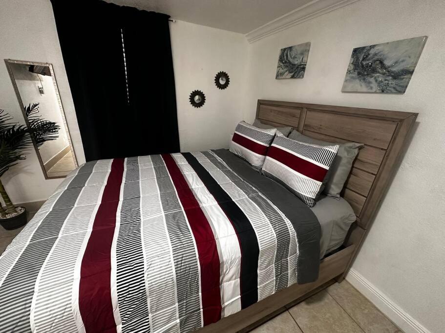 Schlafzimmer mit einem Bett mit gestreifter Decke in der Unterkunft Miami Breeze Studio in Miami Gardens