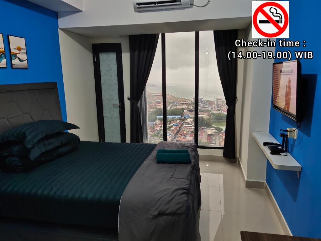 a bedroom with a bed with a view of a city at Comodo Apartemen Pollux Habibie Rooftop-SeaView in Batam Center