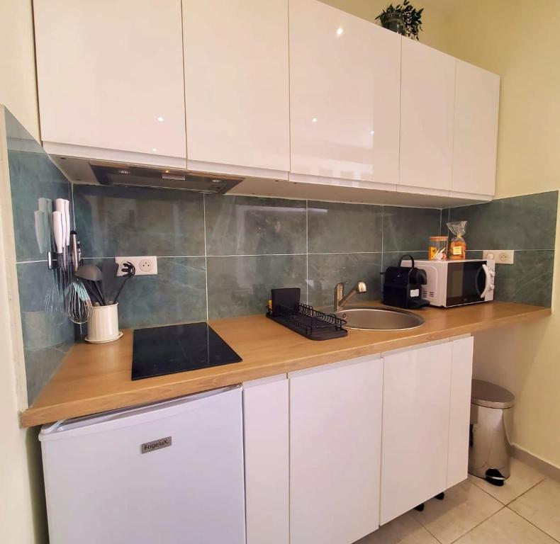 a kitchen with white cabinets and a sink and a microwave at Studio Mezzanine neuf, Monaco à pied, Clim - WIFI in Beausoleil