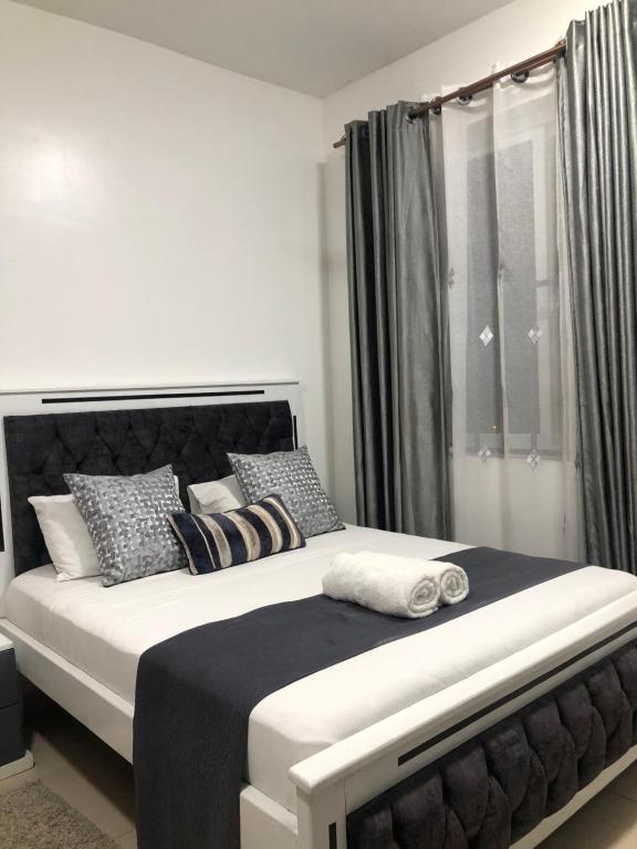ein Schlafzimmer mit einem großen Bett mit schwarzen und weißen Kissen in der Unterkunft Leisure apartment in Mombasa
