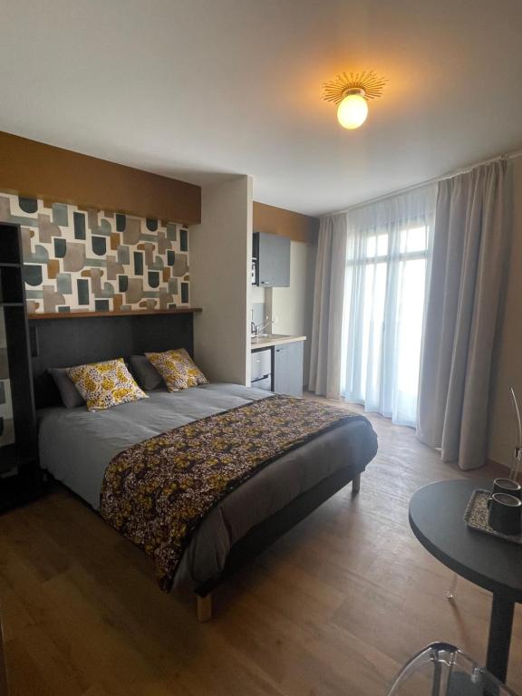 Schlafzimmer mit einem Bett, einem Tisch und einem Fenster in der Unterkunft Smart Appart Le Havre 105 in Le Havre
