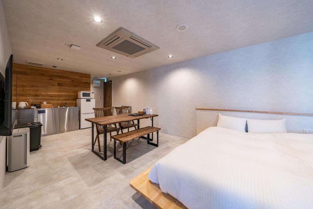 Relax Hotel Takayama Station في تاكاياما: غرفة نوم بسرير وطاولة ومطبخ