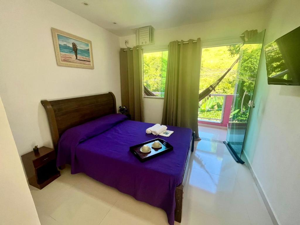 a bedroom with a purple bed with a tray of food on it at Flat Três Praias in Angra dos Reis